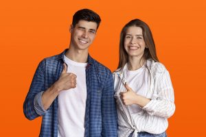 Male and female couple, casually dressed over an orange background